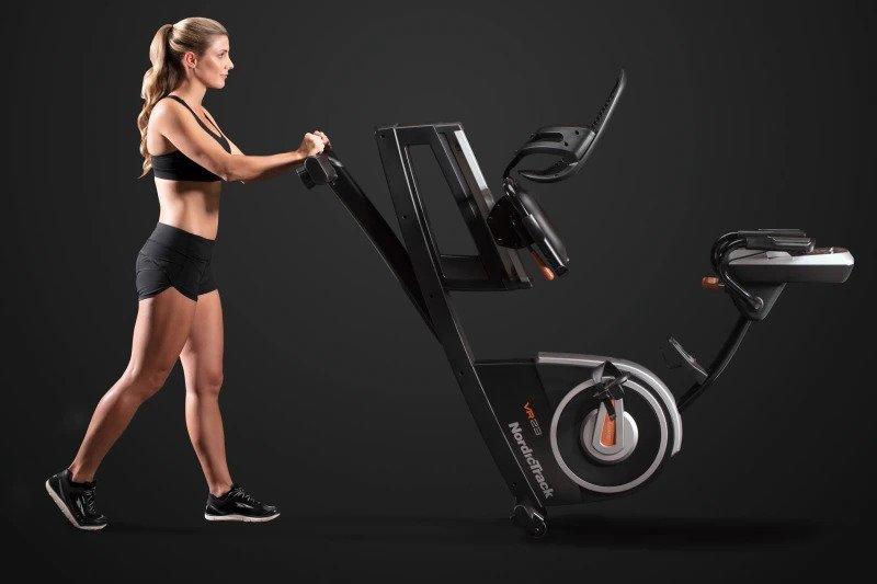 young blonde woman with a black top and shorts tilting the vr21 on it's wheels to move it forward to show how mobile the model is