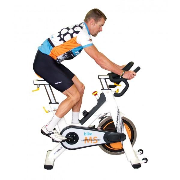 Side view of a man in fitness clothing riding a white, orange, and black exercise bike.