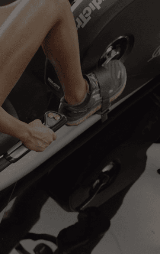 Closeup of a woman in athletic shoes riding an exercise bike.